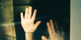 Child's hands pressed against a window, creating a reflective image