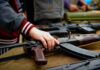 Europol Alarm: Kids Recruited To Kill Hand touching assault rifle on display table