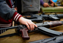 Europol Alarm: Kids Recruited To Kill Hand touching assault rifle on display table