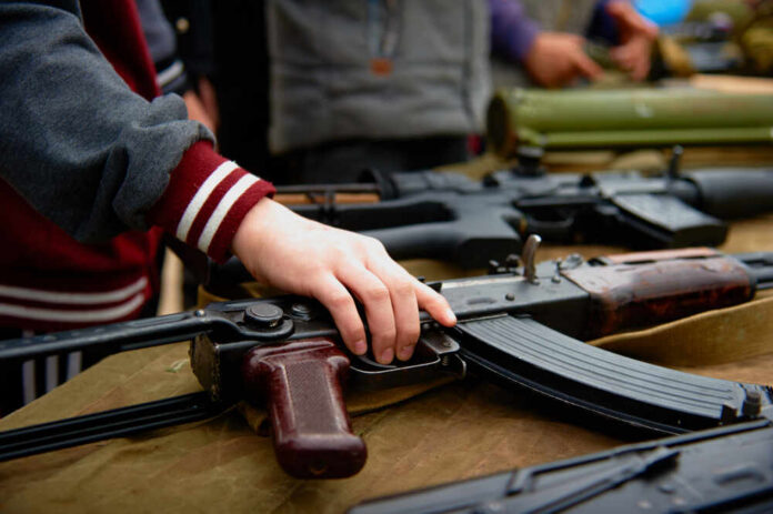 Hand touching assault rifle on display table