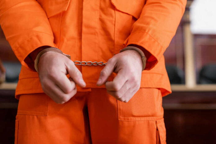 A person in an orange jumpsuit with handcuffs