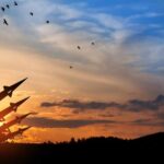 Missiles Fly: Ceasefire Fantasy Dies Silhouette of missiles against a colorful sunset with birds flying