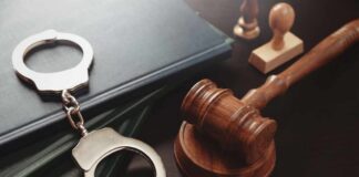 Handcuffs and a gavel on a desk with legal books