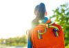 A young person with a colorful backpack standing in sunlight