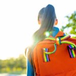 A young person with a colorful backpack standing in sunlight