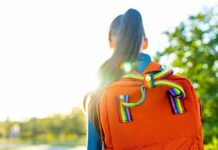 A young person with a colorful backpack standing in sunlight