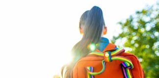 A young person with a colorful backpack standing in sunlight