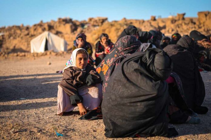 Herat,,Afghanistan,-,Oct,15,,2023:,Herat,Earthquake,Victims A young girl in traditional clothing sitting among a group of women in a refugee camp