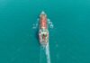 Shadow Deal Triggers Strait Showdown Aerial view of a cargo ship navigating through turquoise waters