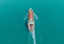 Shadow Deal Triggers Strait Showdown Aerial view of a cargo ship navigating through turquoise waters