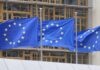 EU Clock Ticks—What Happens After 2027? Three European Union flags waving in front of a building