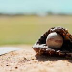 Baseball in a worn glove on the infield dirt