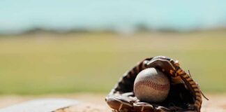 Baseball in a worn glove on the infield dirt
