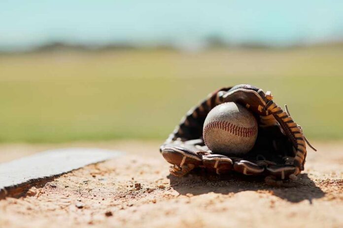 Baseball in a worn glove on the infield dirt