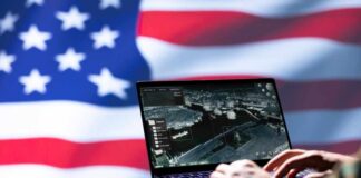 Laptop with surveillance software against a blurred American flag