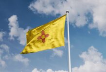 Yellow flag with red Zia sun symbol waving on a flagpole