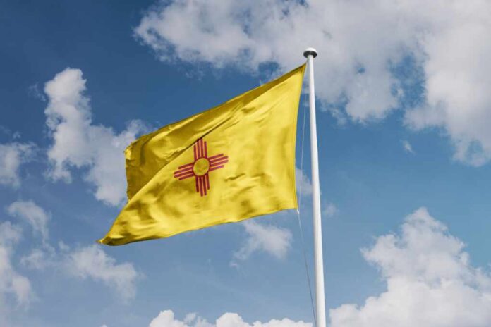 Yellow flag with red Zia sun symbol waving on a flagpole