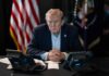 High Court Reshapes Presidential Authority A serious-looking man seated at a table with phones and an American flag in the background
