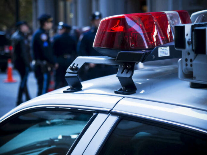 shutterstock_46269745 Close-up of a police car with red lights and officers in the background