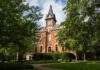 Universities Putting Politics Above Truth? Students walking past a historic stone archway and ornate gate on a university campus