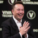 Smiling speaker at a technology conference with hands clasped together