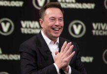 Smiling speaker at a technology conference with hands clasped together