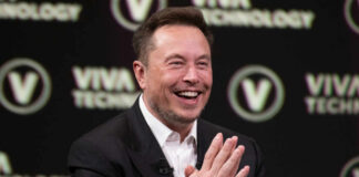 Smiling speaker at a technology conference with hands clasped together
