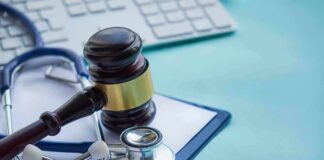 Gavel and stethoscope on medical clipboard near keyboard