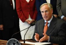 Texas Flood Victims Await Federal Relief man in suit speaking at a podium with a microphone
