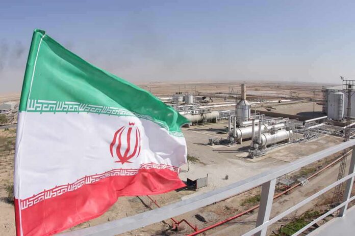 Iran flag over an oil and gas facility in a desert landscape