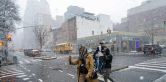 People crossing a snowy street in an urban area during a winter storm