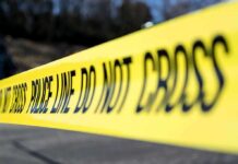 Gun Ban Failed To Stop Killer Yellow police tape stretched across an outdoor scene
