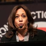 Kamala Harris’ Malibu Home Sparks Questions woman speaking at a podium with microphone