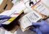 ICE Bust Uncovers Hidden SIM Farms Gloved hands handling labeled evidence bags and boxes