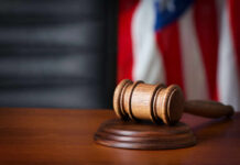 Supreme Court Greenlights Late Mail Votes A wooden gavel resting on a round base with a blurred American flag in the background