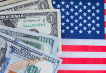 Washington’s Budget Crisis Deepens Various denominations of US dollar bills on an American flag background
