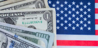 Various denominations of US dollar bills on an American flag background