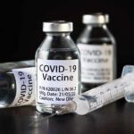 Vaccine Lawsuits Back On The Table Vials of COVID-19 vaccine and a syringe on a dark background