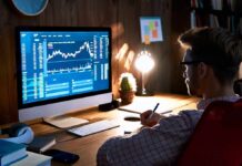 Man analyzing stock charts on desktop computer at desk