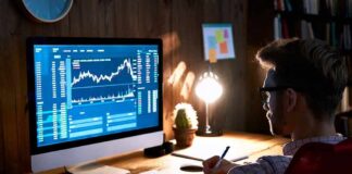 Man analyzing stock charts on desktop computer at desk