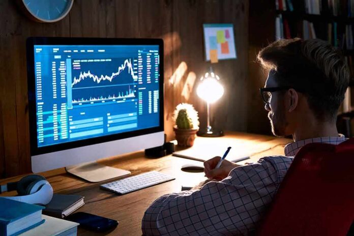 Man analyzing stock charts on desktop computer at desk
