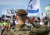 Israeli Court Delivers Harsh Spy Sentence Soldier saluting in front of a crowd with the Israeli flag in the background