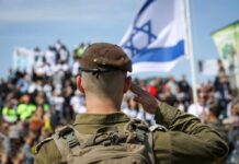Israeli Court Delivers Harsh Spy Sentence Soldier saluting in front of a crowd with the Israeli flag in the background