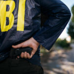 FBI agent gripping handgun near waistband outdoors