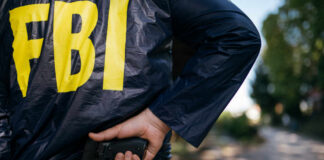 FBI agent gripping handgun near waistband outdoors