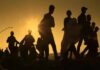 Silhouettes of people walking at sunset
