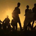 Silhouettes of people walking at sunset