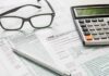 Tax forms with calculator, glasses, and pen
