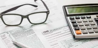 Tax forms with calculator, glasses, and pen