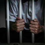 person gripping prison bars